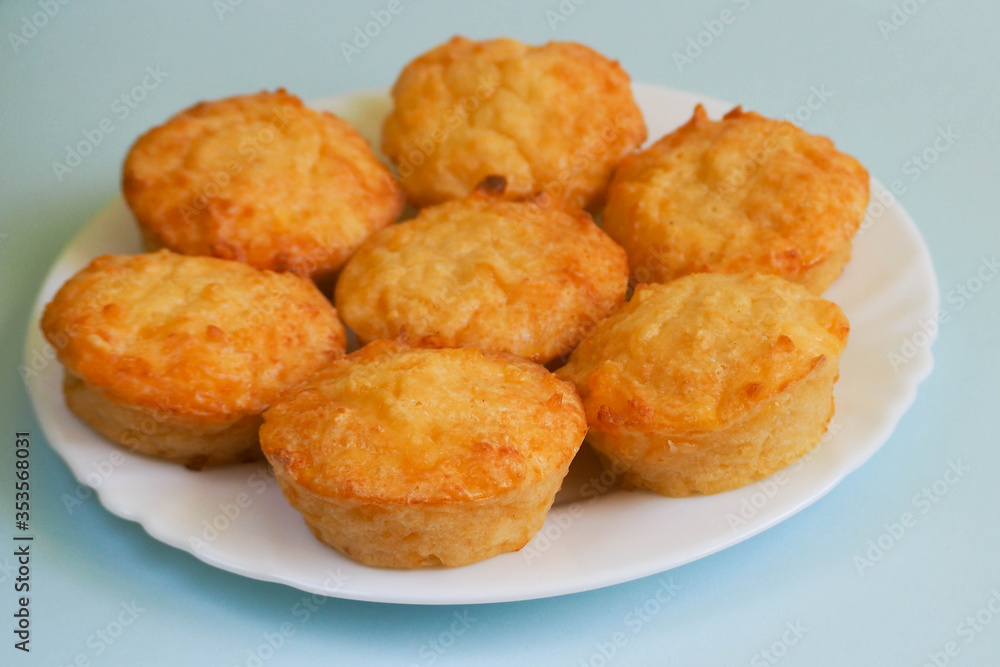 seven cheese muffins made of cottage cheese, eggs and rice flour on a white round plate on a light blue background side view . gluten-free food prepared at home. bakery products