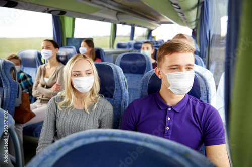tourism, pandemic and health care concept - couple with group of passengers or tourists wearing face protective medical mask for protection from virus disease in travel bus © Syda Productions