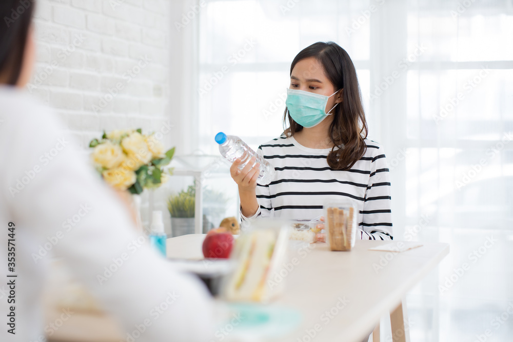 Young Asian woman sitting separated in restaurant or home eating food with table protect infection from coronavirus covid-19, new normal restaurant and social distancing concept. Young Asian woman sitting separated in restaurant or home eating food with table protect infection from coronavirus covid-19, new normal restaurant and social distancing concept.