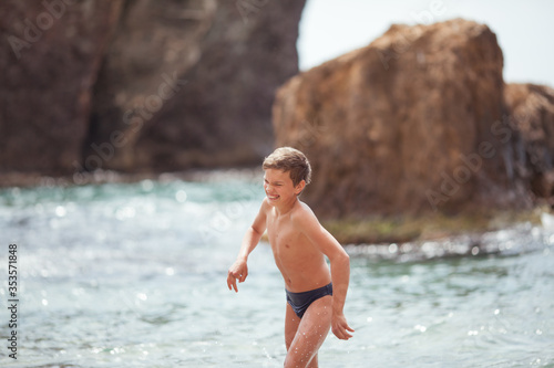 Happy beautiful teenager is swimming in the sea, a boy comes out of the water