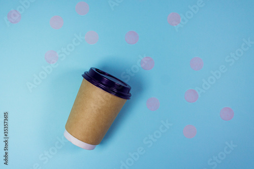 Coffee to go concept. Disposable craft cup with black plastic cover with pastel pink confetti on pastel blue background. Place for text. Flat lay style. Top view