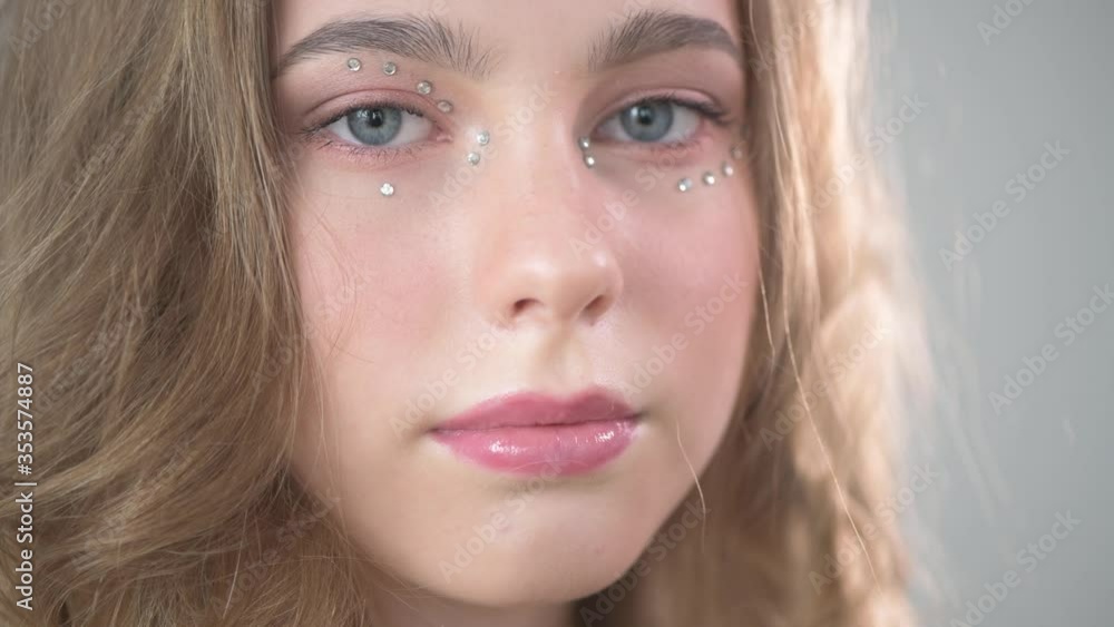 The girl with gentle make-up looks to the side afterwards at the camera. The girl with gentle make-up looks to the side afterwards at the camera.