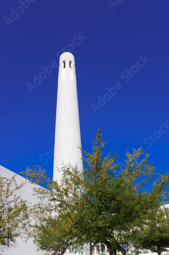 Bright white Msheireb Mosque Minaret against blue sky on a sunny day
