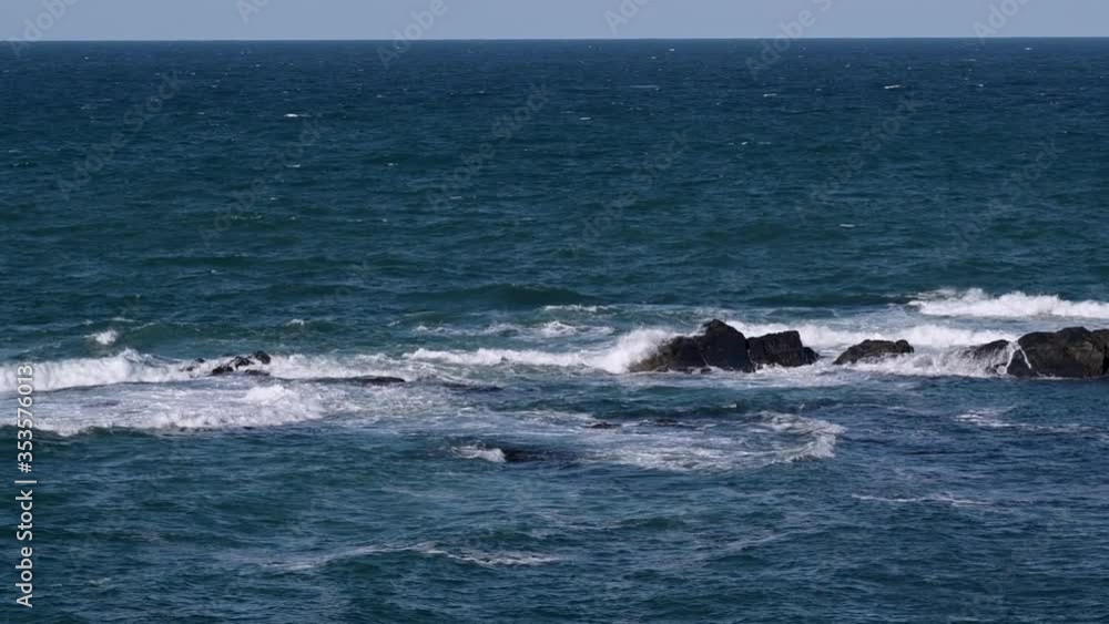 Looking out over a vast empty ocean as small wind driven waves erode an isolated rock outcrop Looking out over a vast empty ocean as small wind driven waves erode an isolated rock outcrop