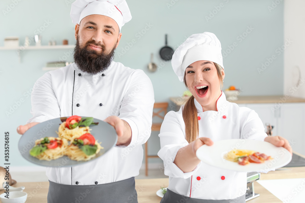 Male and female chefs with tasty dishes in kitchen