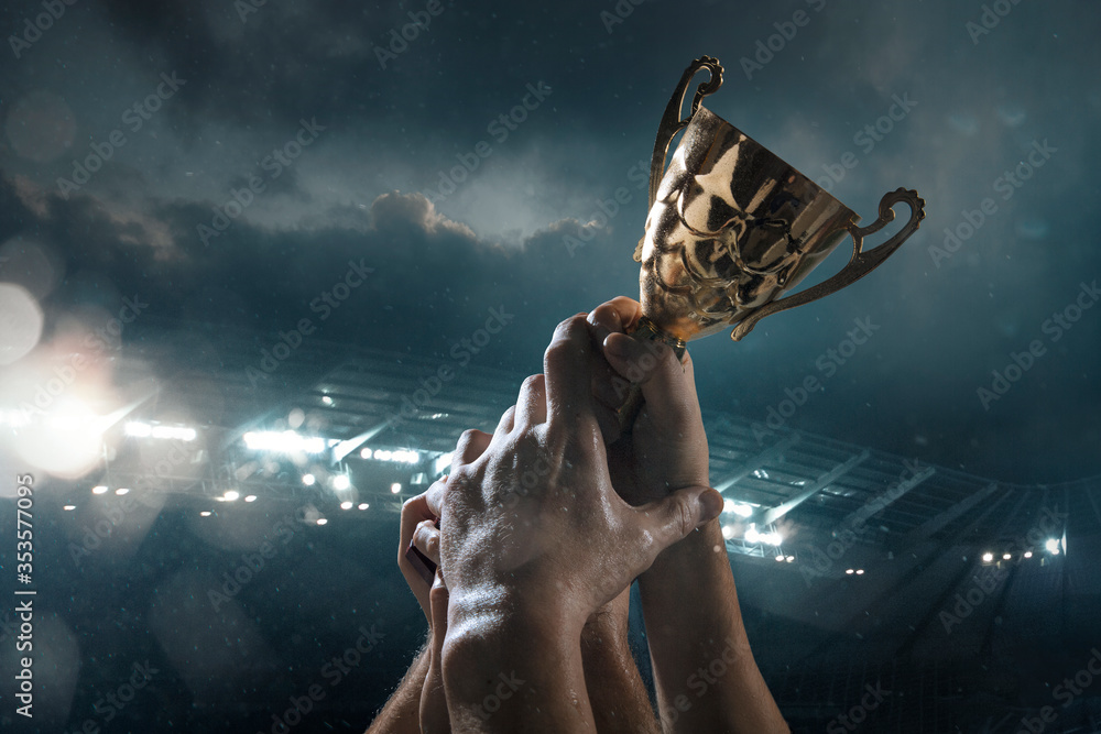 Fototapeta premium Hard work. Award of victory, male hands tightening the golden cup of winners against cloudy dark sky. Sport, competition, championship, winning, achieving the goal. Prize for success and honor.