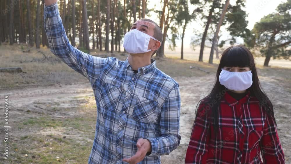 A man and a woman walking in a pine forest in the fresh air. A young couple are protected by face masks. Prevention of infection during an epidemic. A man and a woman walking in a pine forest in the fresh air. A young couple are protected by face masks. Prevention of infection during an epidemic.