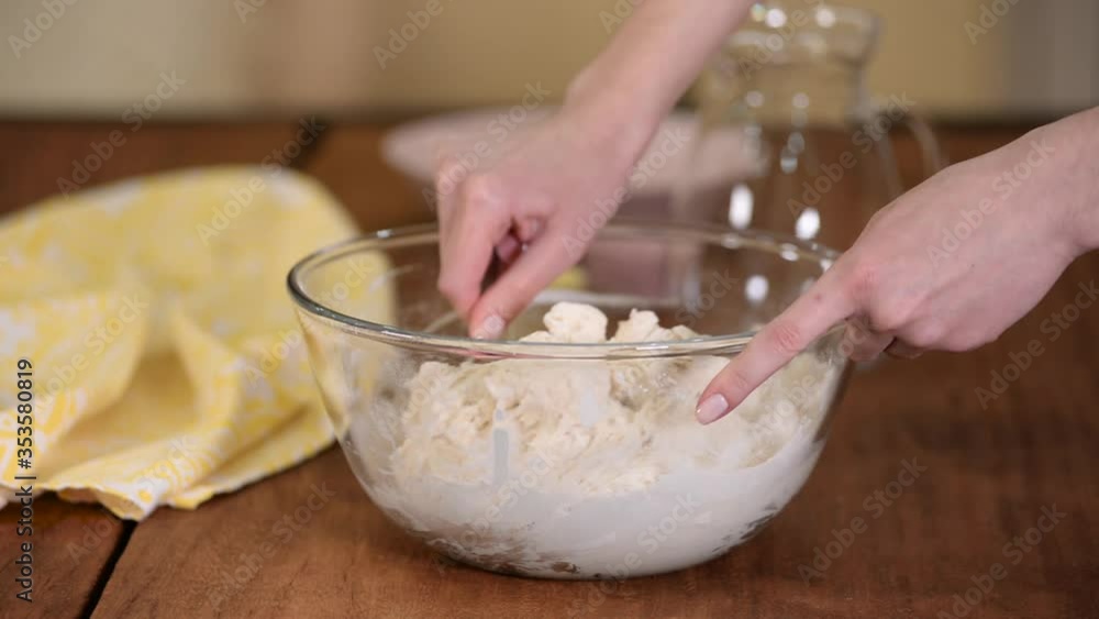 Female preparing and knead the dough in bowl.