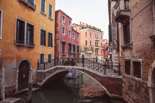 Two lovers sitting side by side on a bridge over a canal among old buildings in Venice, Italy