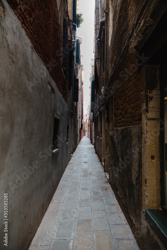 An empty alley with brown brick walls in daylight Venice, Italy. Light at the end of the tunnel.