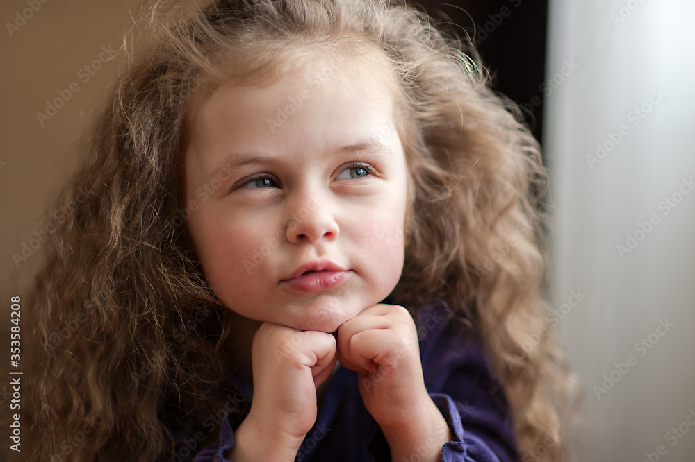 Closeup portrait of a cute toddler girl with her curly hair at home near the window Closeup portrait of a cute toddler girl with her curly hair at home near the window