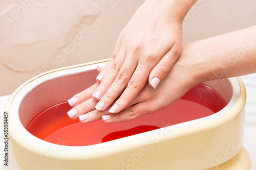 The process of paraffin therapy of a female hand is shot close up in a beauty salon. photo