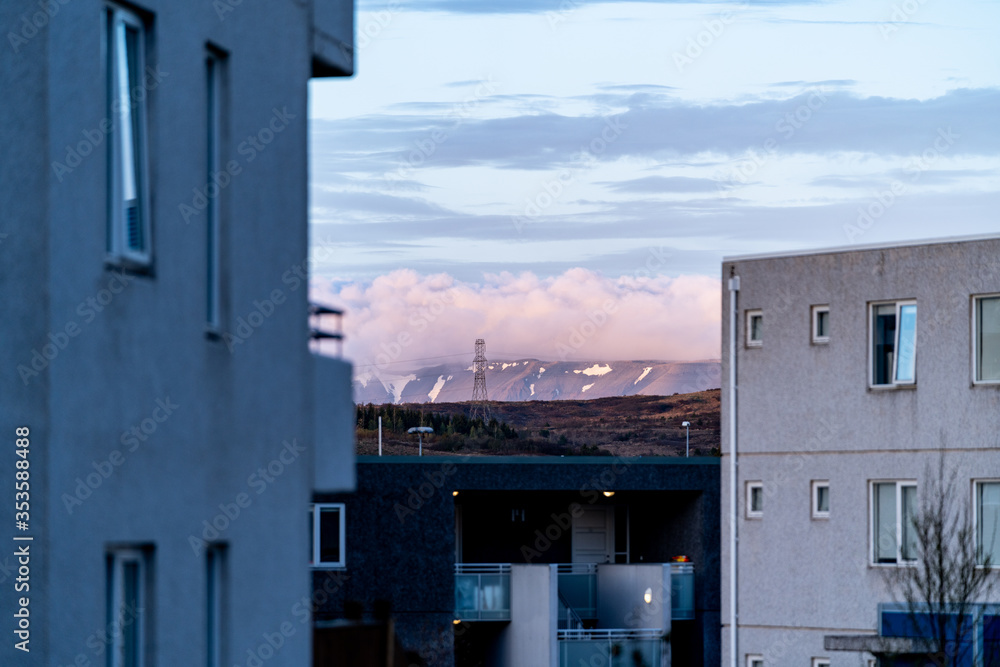 Two old concrete buildings in front of a mountain in the sunset. There are clouds over the mountain and the mountain is partly snow covered. Two old concrete buildings in front of a mountain in the sunset. There are clouds over the mountain and the mountain is partly snow covered.