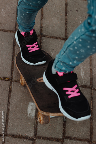 Children's feet on a skateboard, on the asphalt