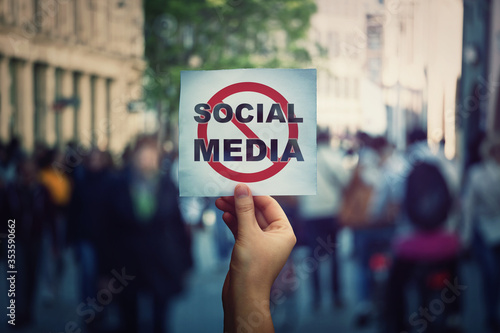 Social media censorship, political war between US president banning social networks. Hand holding a banner with forbidden sign over a crowded street background. Internet communication risk concept. photo