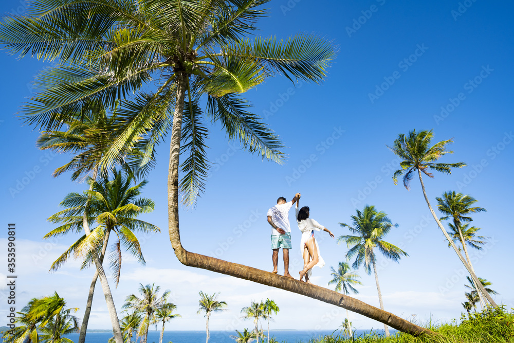 A young couple is posing for a picture on a bent palm tree in Corregidor Island. Corregidor Island Siargao, also known as Casolian Island, is a dreamy tropical island in the south of the Philippines.