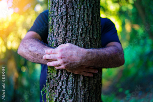 Man hugging a tree in the forest. Eco-friendly concept. Against deforestation. Taking care of forests.