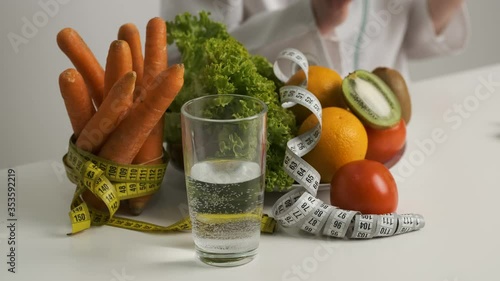 Vegetables and fruits on the table for a healthy diet. Diet. Lettuce, carrots, a glass of water, kiwi, tomato, orange and measuring tape photo