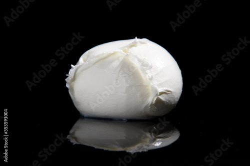 production buffalo mozzarella cheese from Campania region Italy on a black mirrored background with cutting light photo