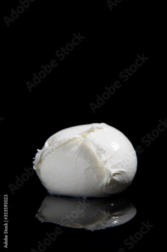 mozzarella cheese from Campania region Italy on a black mirrored background with cutting light
