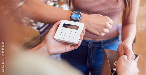 Woman In Clothing Store Making Contactless Payment With Smart Watch At Sales Desk