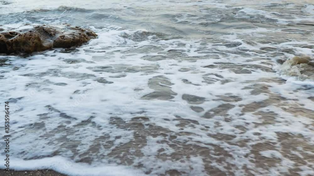 Waves come over the beach sand passing the rocks and then recede back to come again Waves come over the beach sand passing the rocks and then recede back to come again
