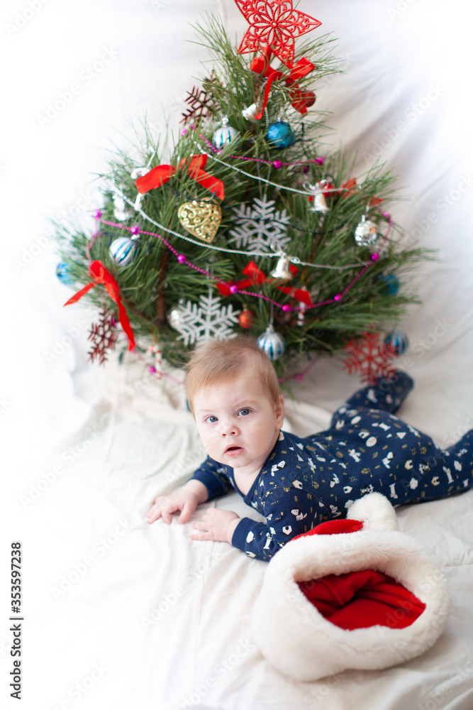 infant in santa hat near christmas tree new year infant in santa hat near christmas tree new year