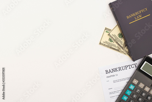 top view of bankruptcy paper and law book, money and calculator on white background