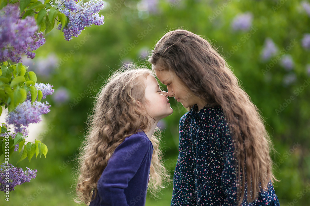 Outside is a portrait of two sisters among the lilac bushes. Outside is a portrait of two sisters among the lilac bushes.