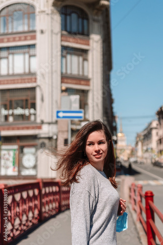 The girl went outside after the quarantine, walking around the city on the red bridge in St. Petersburg