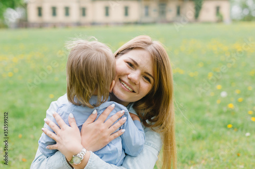 Mom and son are playing on the lawn. Mom and child are walking in the park. Relations between mom and son. Walk with the son. © Marina