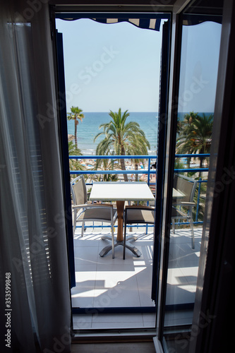 Table and chairs on balcony with palm trees and seascape at background in Catalonia, Spain