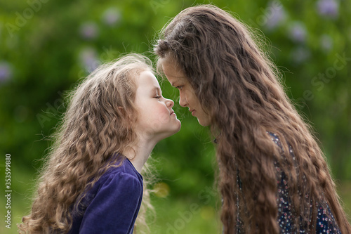 Принти на полотні Outside is a portrait of two sisters among the lilac bushes.