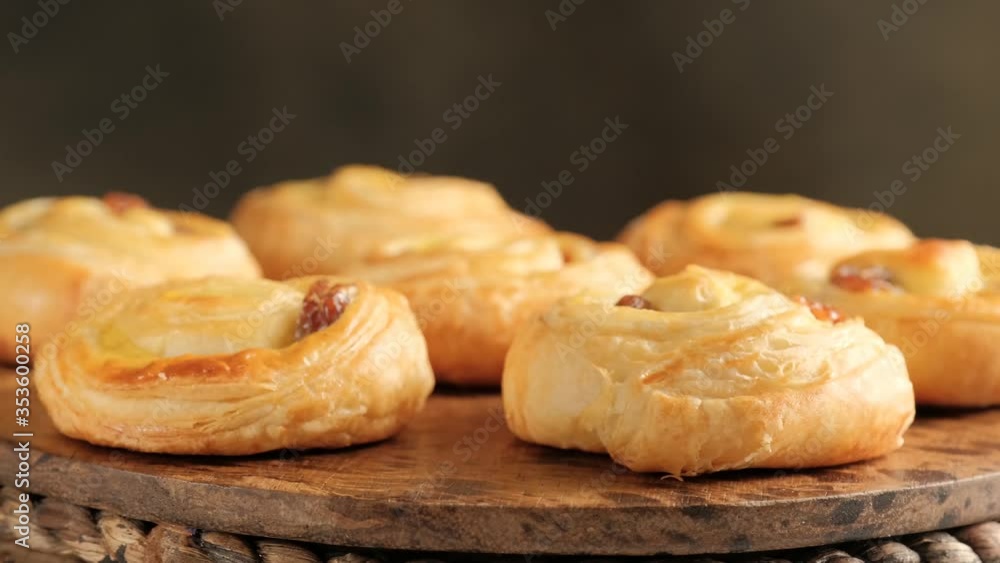 Rotating of fresh pastry sweet swirl buns with raisins on wooden board for breakfast or brunch. Party food concept. Rotating of fresh pastry sweet swirl buns with raisins on wooden board for breakfast or brunch. Party food concept.