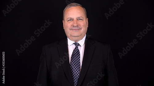 Old businessman in a suit smiling. Isolated black background. 4k