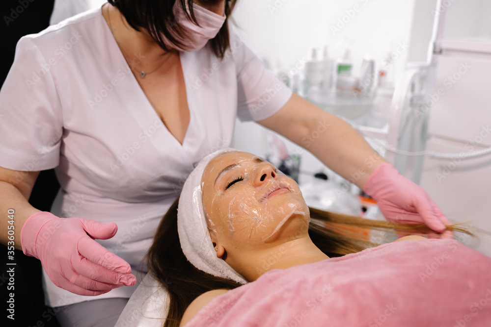 Obraz premium Beautician removes a clay mask from the face of a young girl in the Spa salon. Beautiful young girl at the beautician does the spa procedures