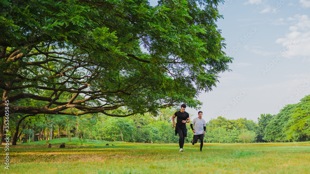 Young man running in the green park with friend Young man running in the green park with friend