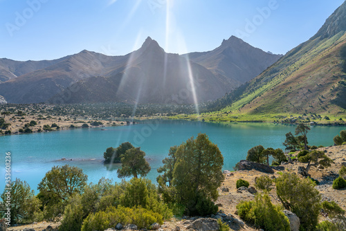 The Pamir range view and peaceful campsite on Kulikalon lake in Fann mountains in Tajikistan. Amasing colorful reflection in pure ice lake.