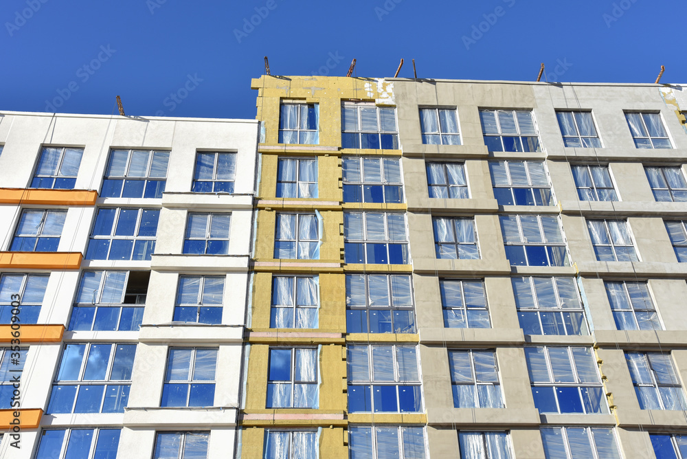 Construction of a new multi-storey building. Wall painting and insulation of the facade of the mineral wool. Modern residential building. Housing renovation program Construction of a new multi-storey building. Wall painting and insulation of the facade of the mineral wool. Modern residential building. Housing renovation program