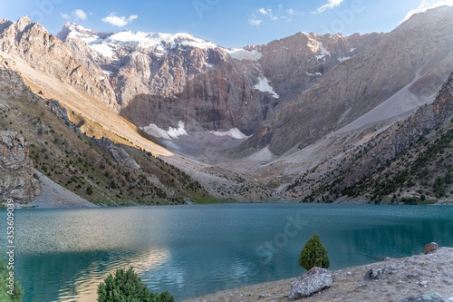 The Pamir range view and peaceful campsite on Kulikalon lake in Fann mountains in Tajikistan. Amasing colorful reflection in pure ice lake.