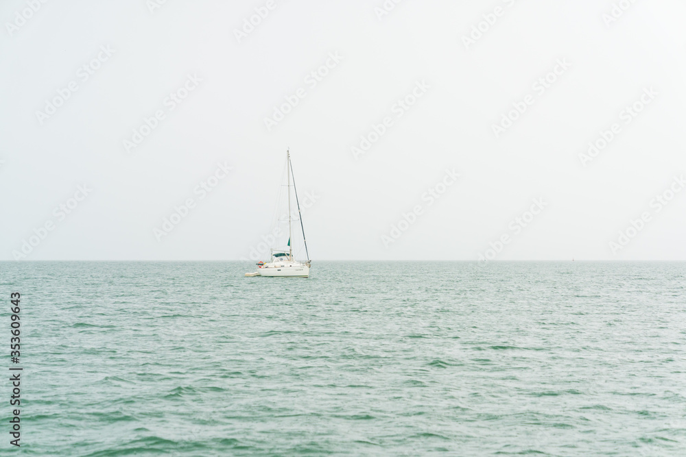 Small sailing boat in the rain in the middle of the sea