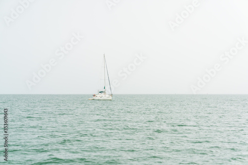 Small sailing boat in the rain in the middle of the sea