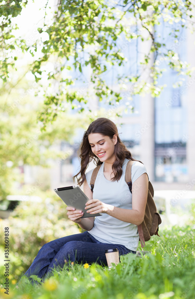 Young beautiful woman using digital tablet in a city park. Smiling girl resting outdoor. Student lifestyle, connection, business, freelance work, education concept Young beautiful woman using digital tablet in a city park. Smiling girl resting outdoor. Student lifestyle, connection, business, freelance work, education concept