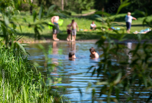 Children (out of focus) swimming in nature, in the River Chess at Chorleywood, Hertfordshire UK. Swimming oudoors in natural habitats is allowed during the coronavirus lockdown.