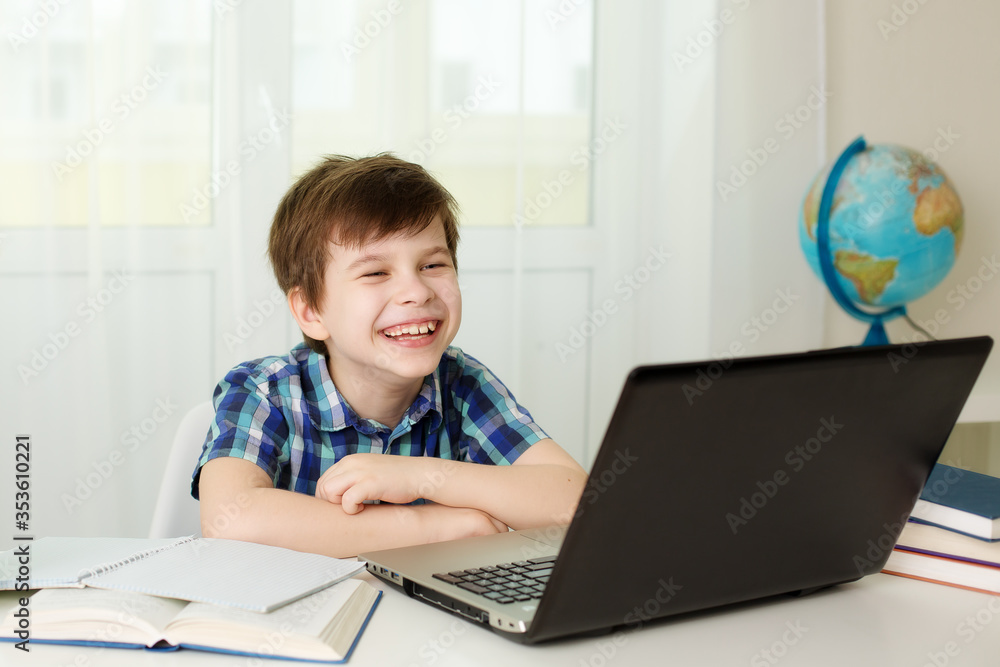 boy laughs and studies at the computer at home boy laughs and studies at the computer at home