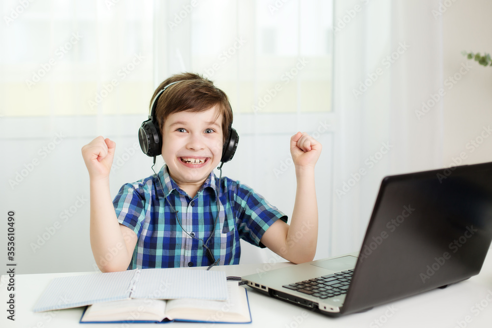 boy with headphones is laughing, studying at the computer at home boy with headphones is laughing, studying at the computer at home