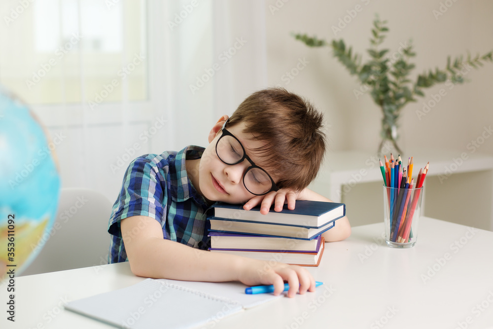 boy with glasses is sitting at the table, writing in a notebook, fell asleep from fatigue boy with glasses is sitting at the table, writing in a notebook, fell asleep from fatigue