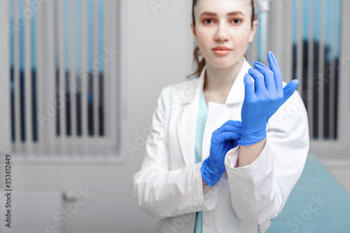 Doctor's hands putting on latex gloves in a hospital. Woman in a doctor's smock in latex gloves. Protection against virus and bacteria. Kovid 19. Health photo