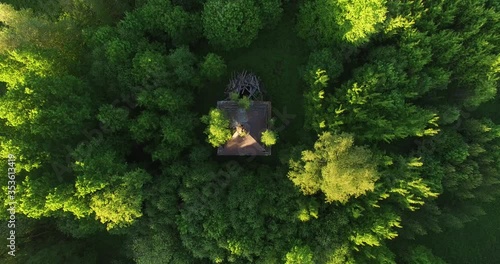 4K early summer sunny afternoon aerial video footage of abandoned village with ruins of houses and church in the middle of dense green wild woods in Russia's Yaroslavl region