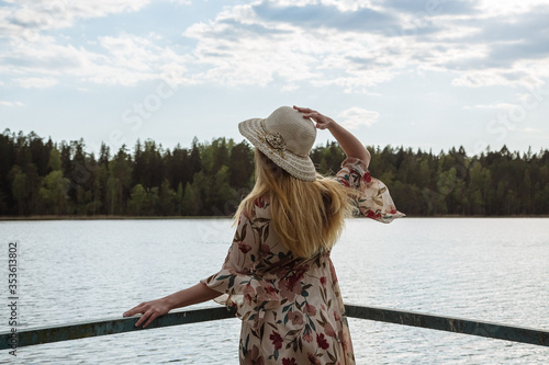 A girl in a beautiful dress on the shore of a forest lake.